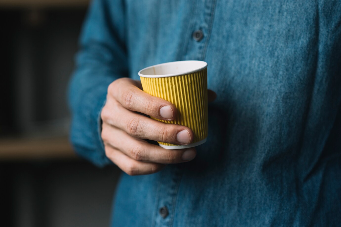 close-up-man-s-hand-holding-disposable-coffee-cup_23-2147937409